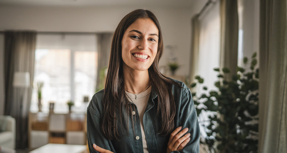 A woman smiling at home, arms folded